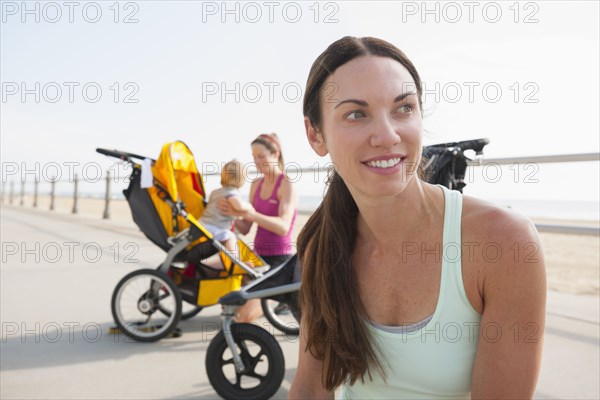 Caucasian mothers with strollers on beach boardwalk