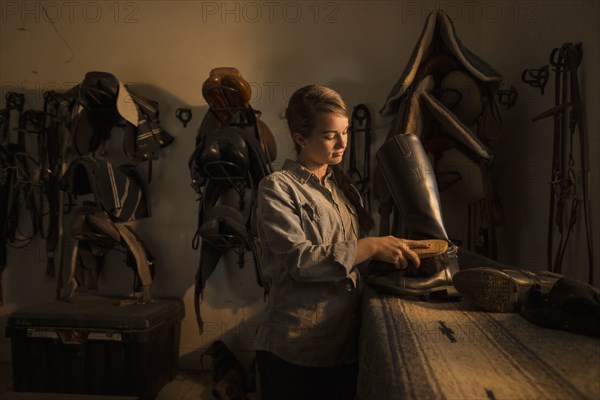 Caucasian girl caring for boots in horse stable