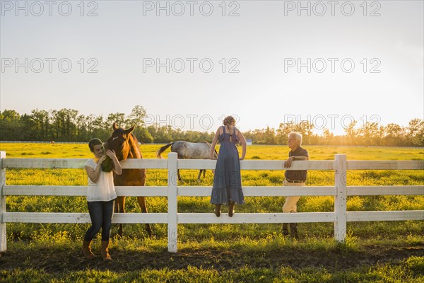 Caucasian family petting horses in rural landscape