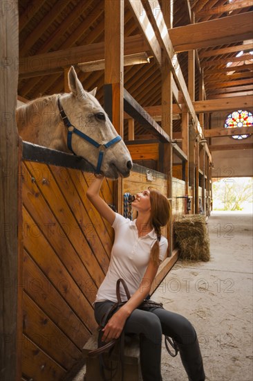 Caucasian girl petting horse in stable