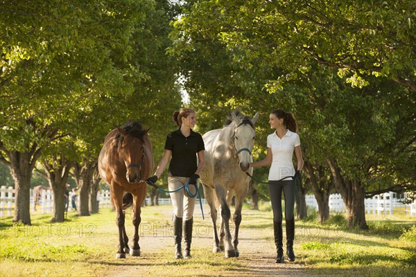 Caucasian girls walking horses on dirt path