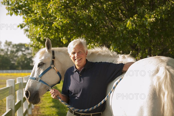 Caucasian man walking horse in rural landscape