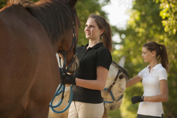 Caucasian girls petting horses in rural landscape