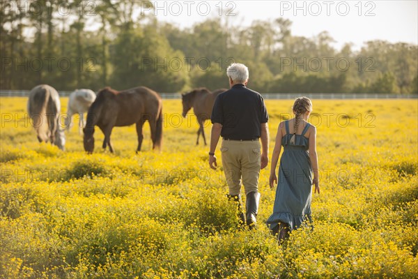 Caucasian man and granddaughter in field with horses