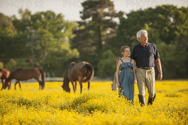 Caucasian man and granddaughter in field with horses