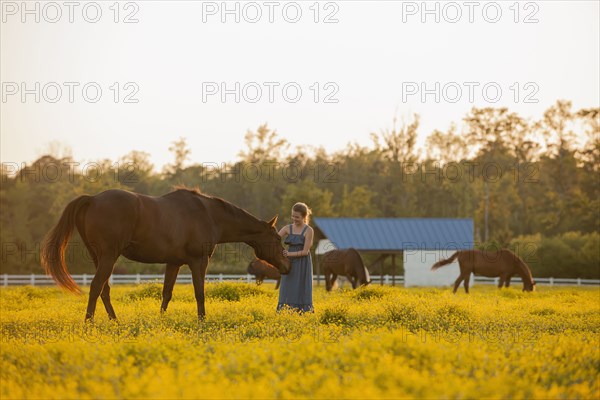 Caucasian girl petting horse in field