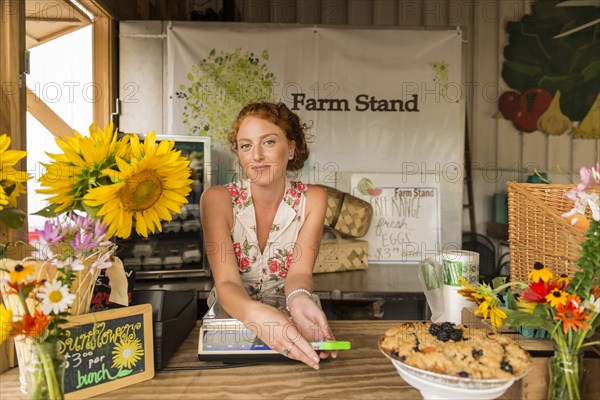 Caucasian woman selling fruit crumble and flowers at farmers market