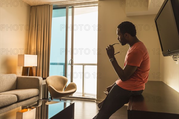 Black man leaning on credenza in living room