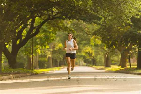 Caucasian woman jogging on neighborhood street