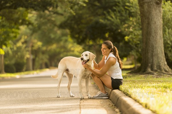 Caucasian woman petting dog on neighborhood street