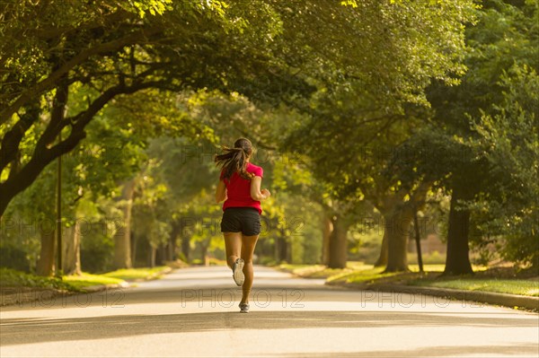 Caucasian woman jogging on neighborhood street