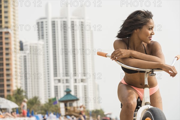 African American woman sitting on bicycle on beach