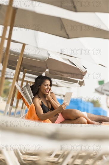 African American woman using digital tablet on beach