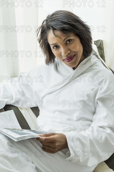 African American woman reading magazine in bathrobe