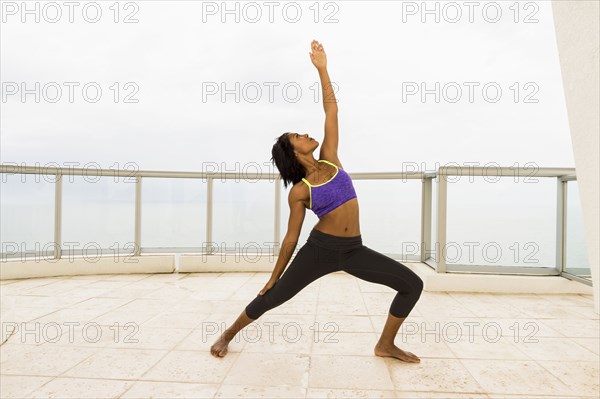 African American woman practicing yoga on balcony