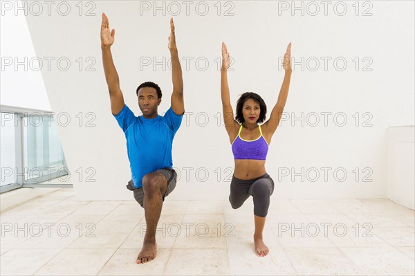 Couple practicing yoga on balcony