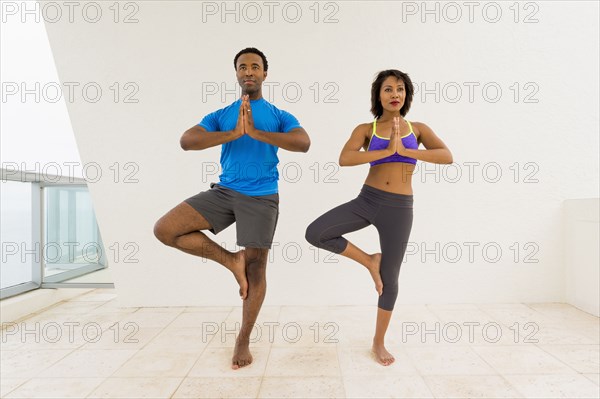 Couple practicing yoga on balcony