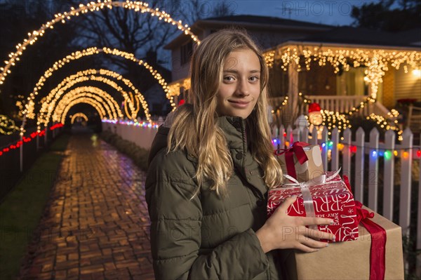 Caucasian girl holding Christmas gifts on sidewalk