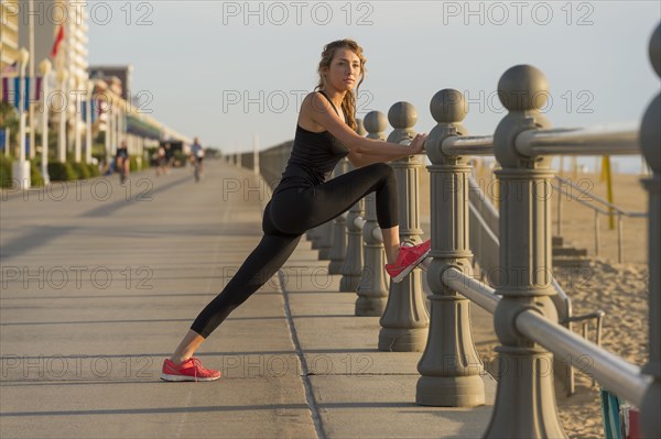 Caucasian teenage girl stretching leg on railing at beach