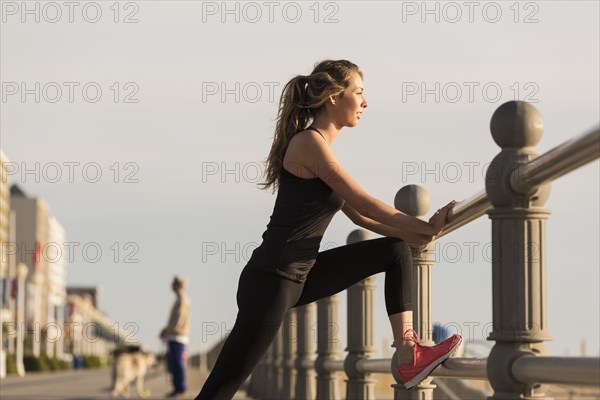 Caucasian teenage girl stretching leg on boardwalk railing