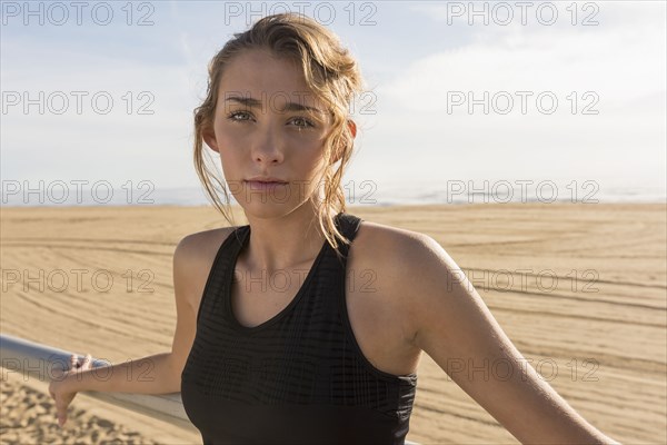 Caucasian teenage girl leaning on railing at beach