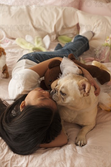 Asian girl laying on bed with dog