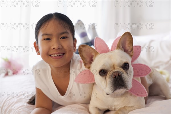 Asian girl laying on bed with costumed dog