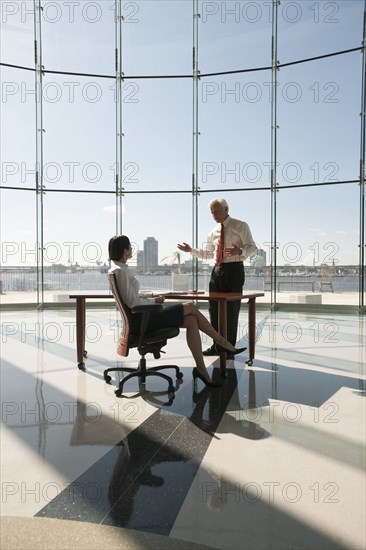 Business people working in large office with glass wall