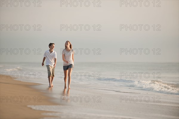 Caucasian brother and sister walking on beach