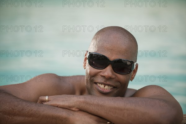 Smiling African American man leaning on edge of swimming pool