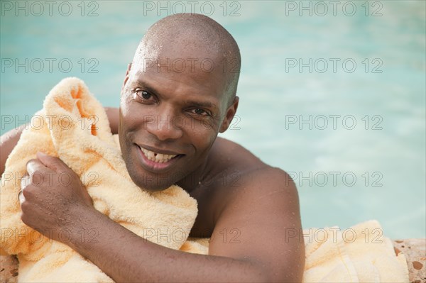 African American man drying off with towel at poolside