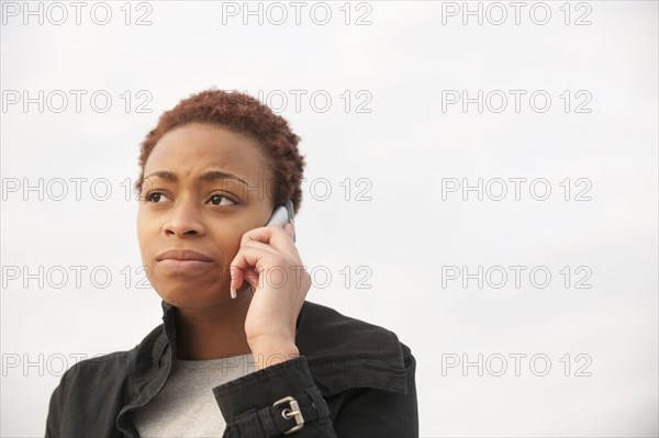 Uncertain African American woman talking on cell phone