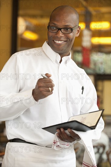 African American waiter holding order pad in restaurant