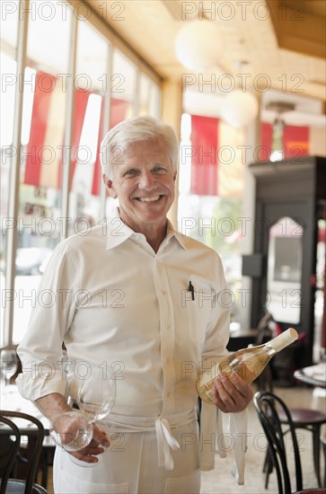 Caucasian waiter holding bottle of white wine