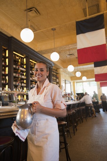 Hispanic waitress holding pitcher in restaurant