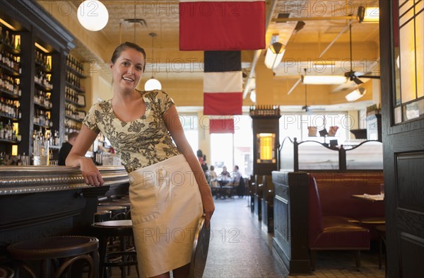 Caucasian waitress leaning on bar in restaurant