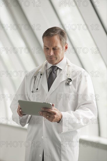 Caucasian doctor using digital tablet in hospital corridor