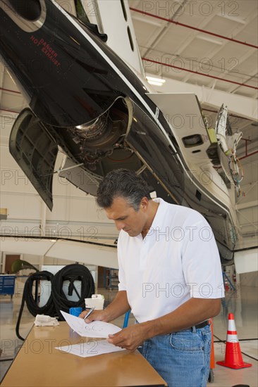 Hispanic man working in airplane hangar