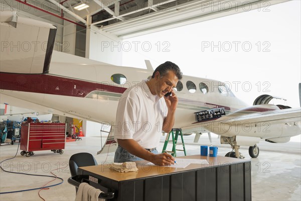 Hispanic man working in airplane hangar