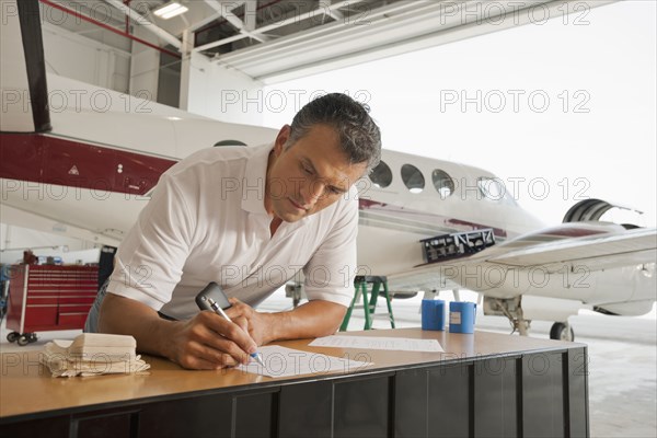 Hispanic man working in airplane hangar