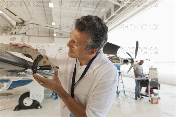 Hispanic man working in airplane hangar