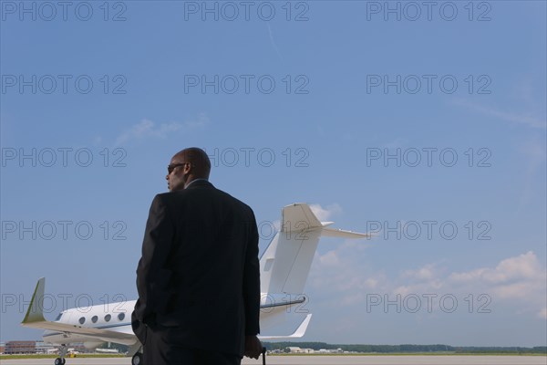 African American businessman standing on airport tarmac