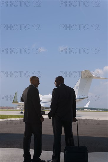 Businessmen standing on airport tarmac