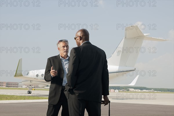 Businessmen standing on airport tarmac