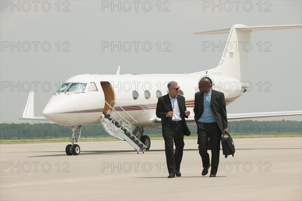 Businessmen walking on airport tarmac