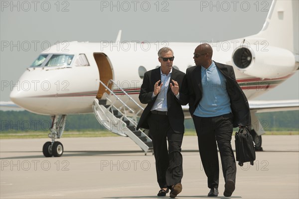 Businessmen walking on airport tarmac