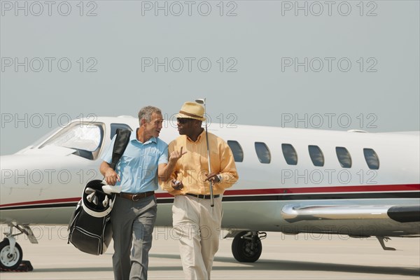 Golfers walking on airport tarmac