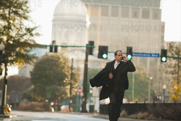 Caucasian businessman walking and talking on cell phone