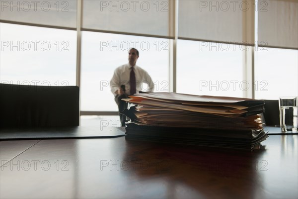 Caucasian businessman sitting behind stack of folders