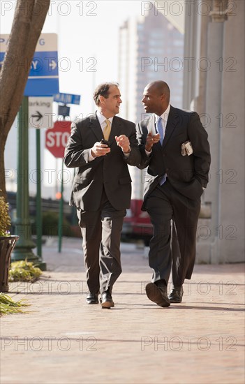 Businessmen walking together on city sidewalk